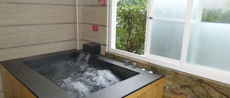 A hot tub with a wooden exterior and a window view.