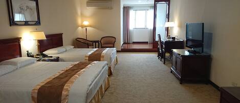 A hotel room with two beds, a desk, a chair, a television, and a mirror.