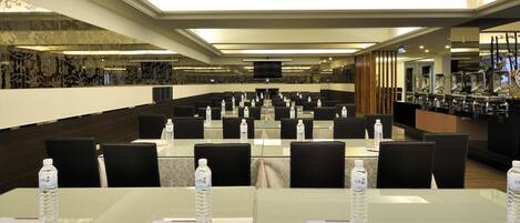 A conference room with multiple tables, chairs, and water bottles.