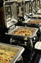 A buffet with various food items in metal serving trays.