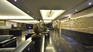 Un moderno vestíbulo de hotel con mostrador de recepción, zona de estar y un arreglo decorativo de plantas.