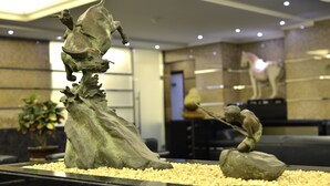 Una escultura de una figura montando un toro, ubicada sobre una plataforma de guijarros.