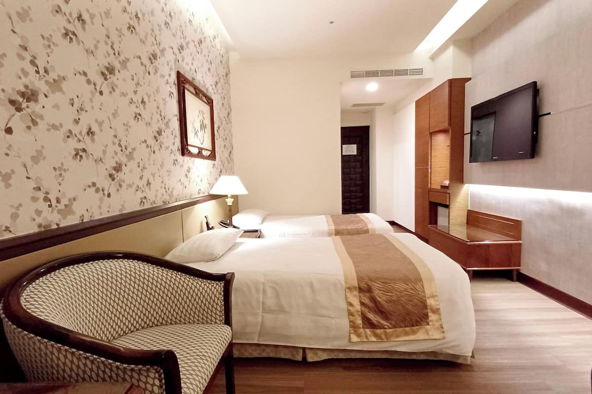 Een hotelkamer met een bed, een stoel, een televisie en een spiegel.