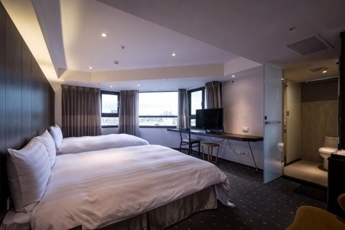 A hotel room with a large bed, a desk with a computer, a television, and a bathroom.
