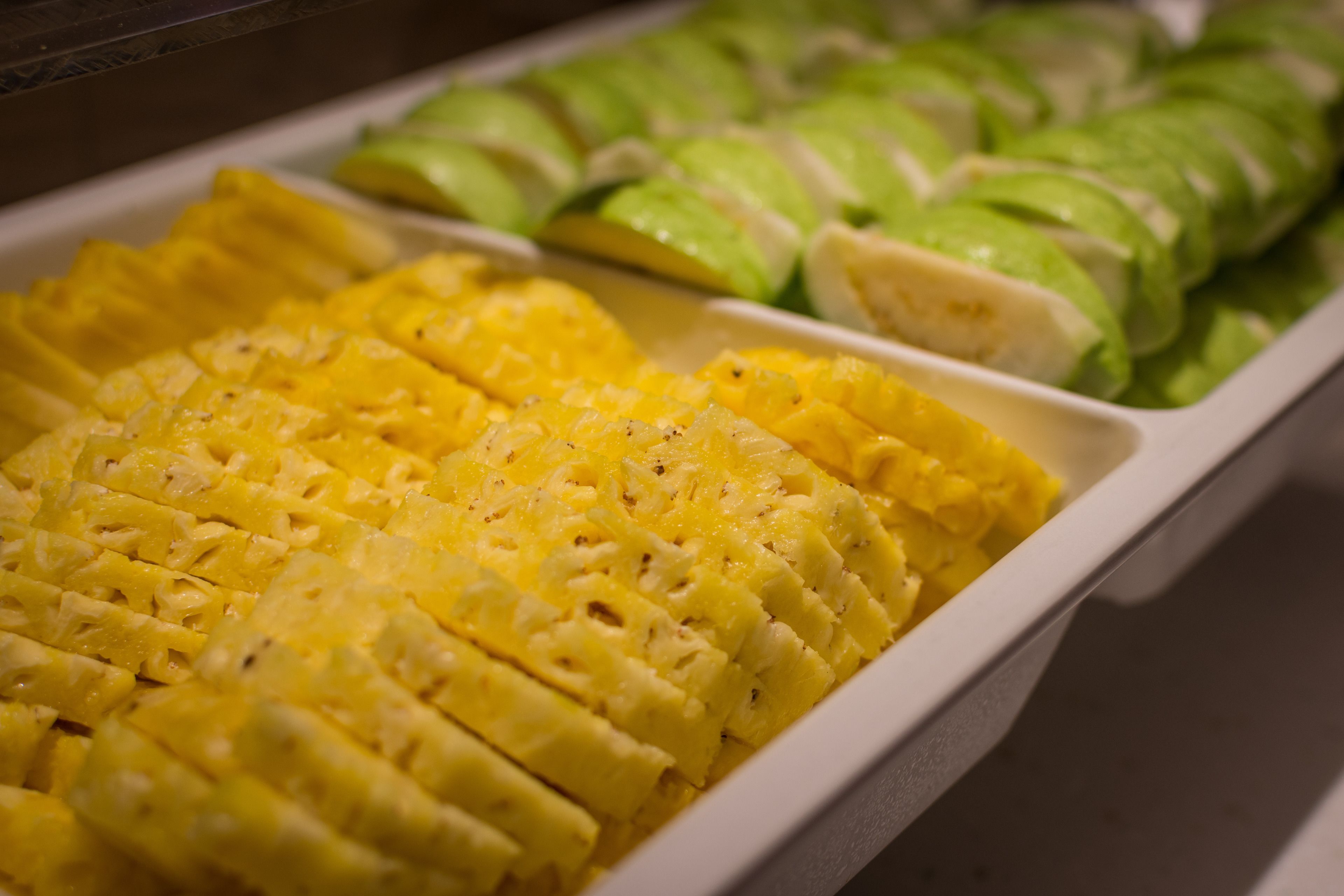 Una bandeja con piña en rodajas y pepino.