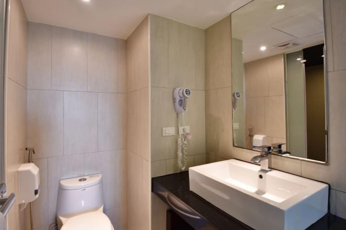 A modern bathroom with a toilet, a sink, a mirror, and a hairdryer.