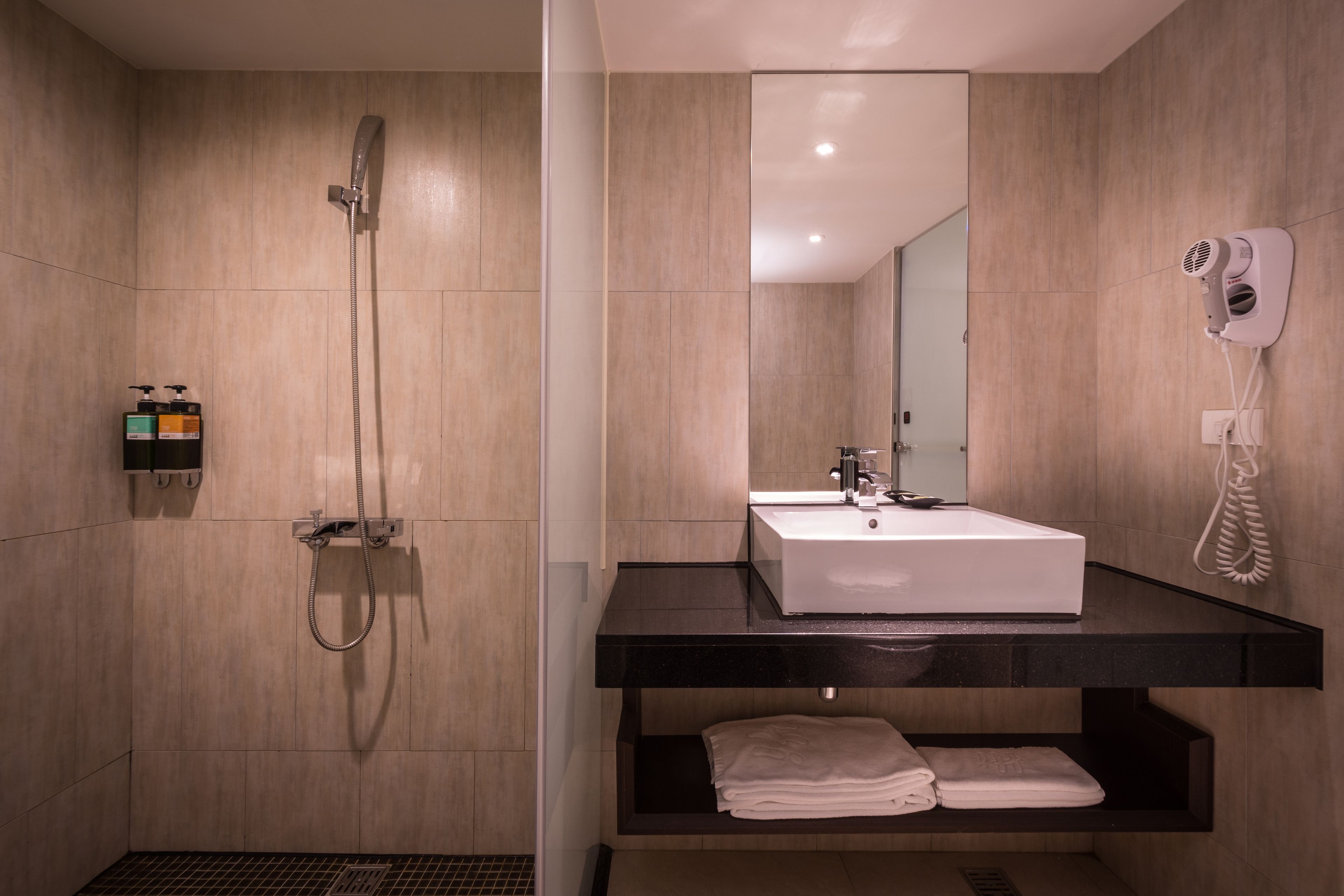 A modern bathroom with a shower, sink, and towel rack.