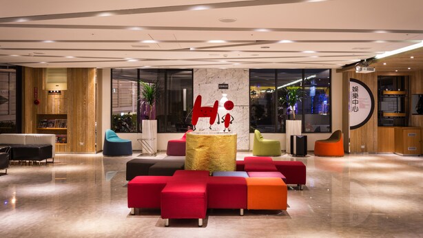 A modern lobby with a central seating area, a reception desk, and a large window providing a view of the cityscape. - Hotel Hi Chuiyang (Chiayi City)