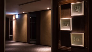 A hallway with framed photographs on the wall, a sign with text, and a door with a handle. - Hotel Hi Chuiyang (Chiayi City)