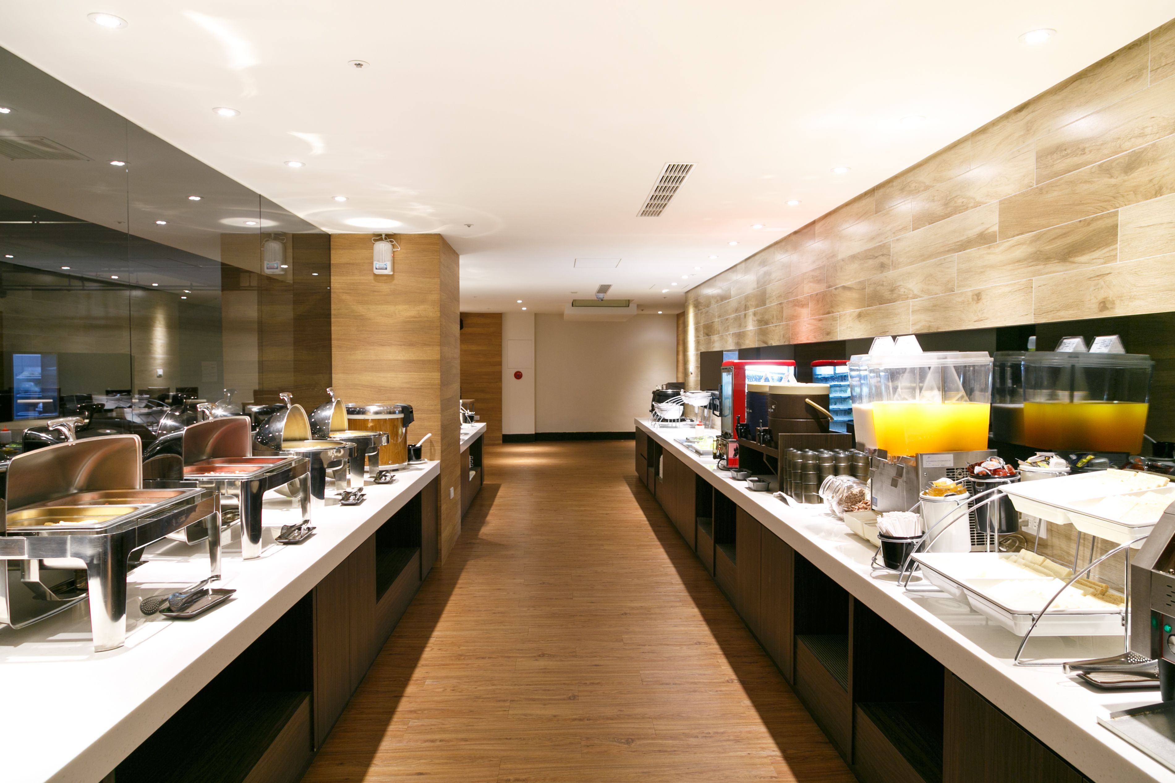Una cocina de hotel moderna con electrodomésticos de acero inoxidable, una encimera larga con diversos alimentos y un suelo de madera.
