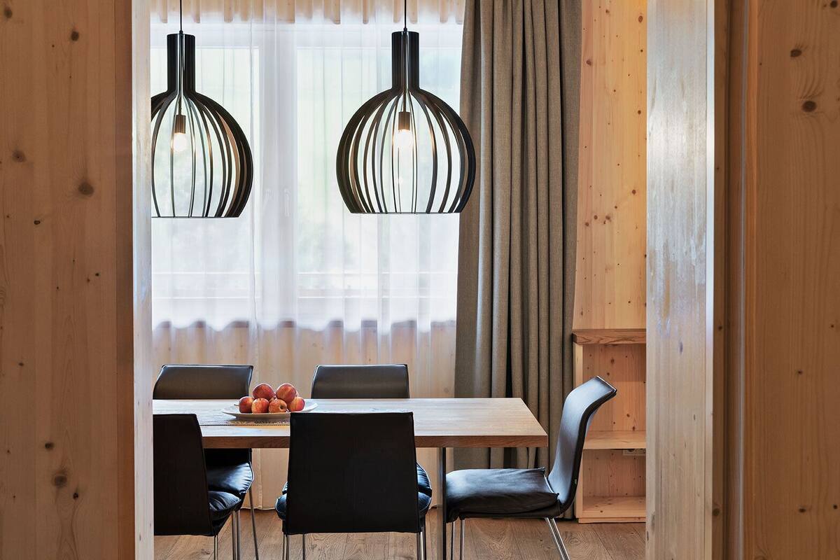 A dining area with a wooden table, black chairs, and a fruit bowl.