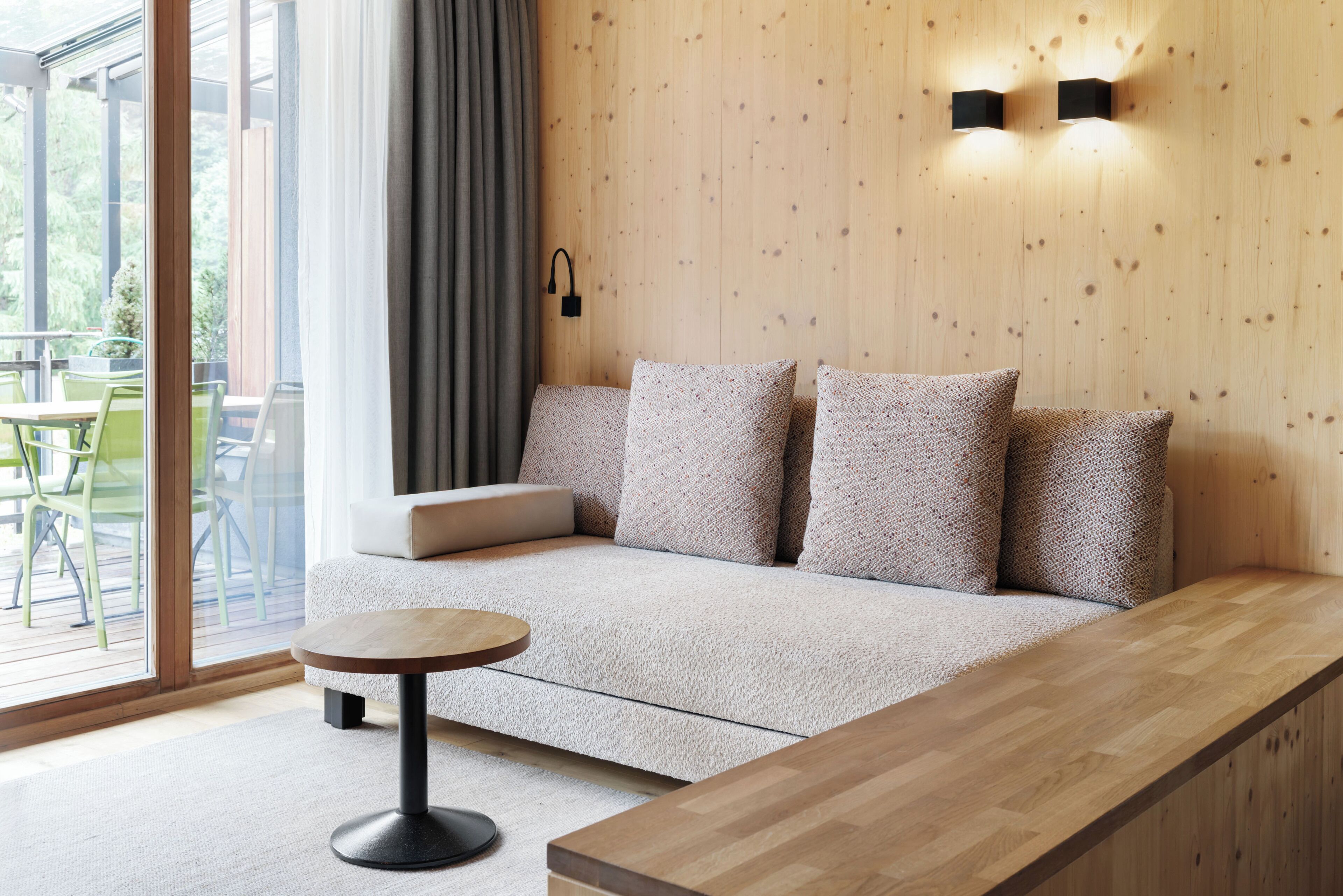 A modern interior with a sofa, a round table, and a wooden bench.