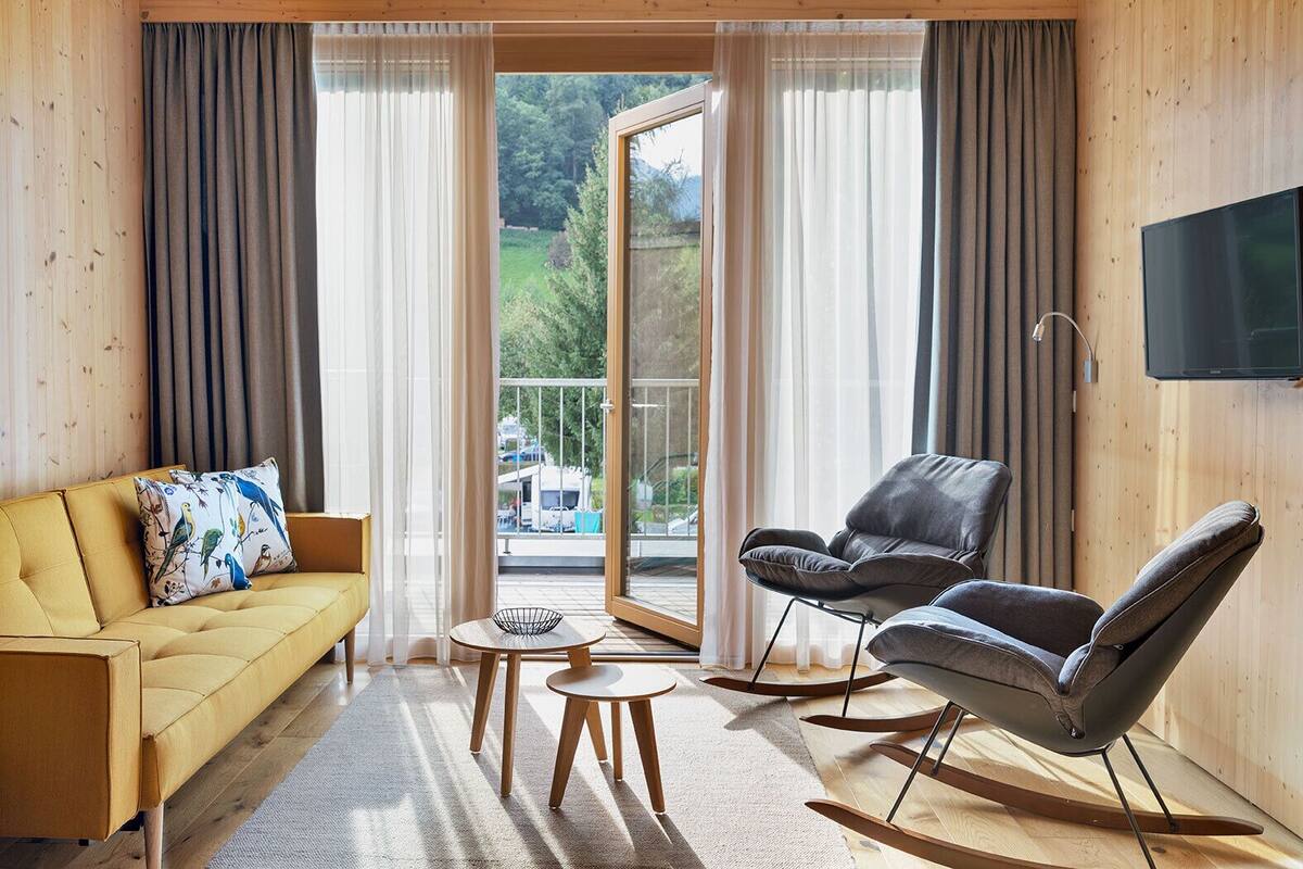 A modern living room with a sofa, two chairs, a small table, and a TV.