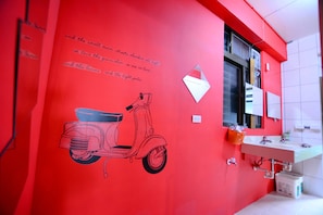 A bathroom with a red wall, a white sink, and a window. - Corner Inn (New Taipei City)