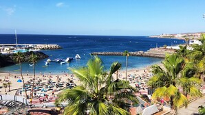 Una playa con palmeras, un muelle y barcos.