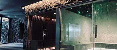 A modern interior with a stone-textured ceiling, a glass partition, and a seating area with a bench and a table.