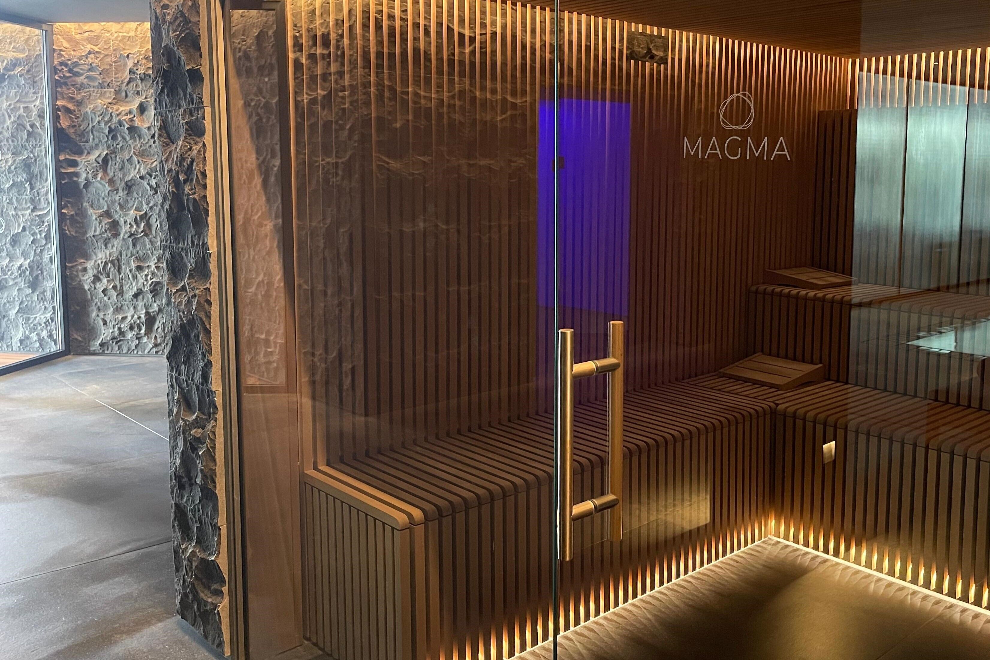 A modern spa area with a stone wall, wooden slats, and a bench.