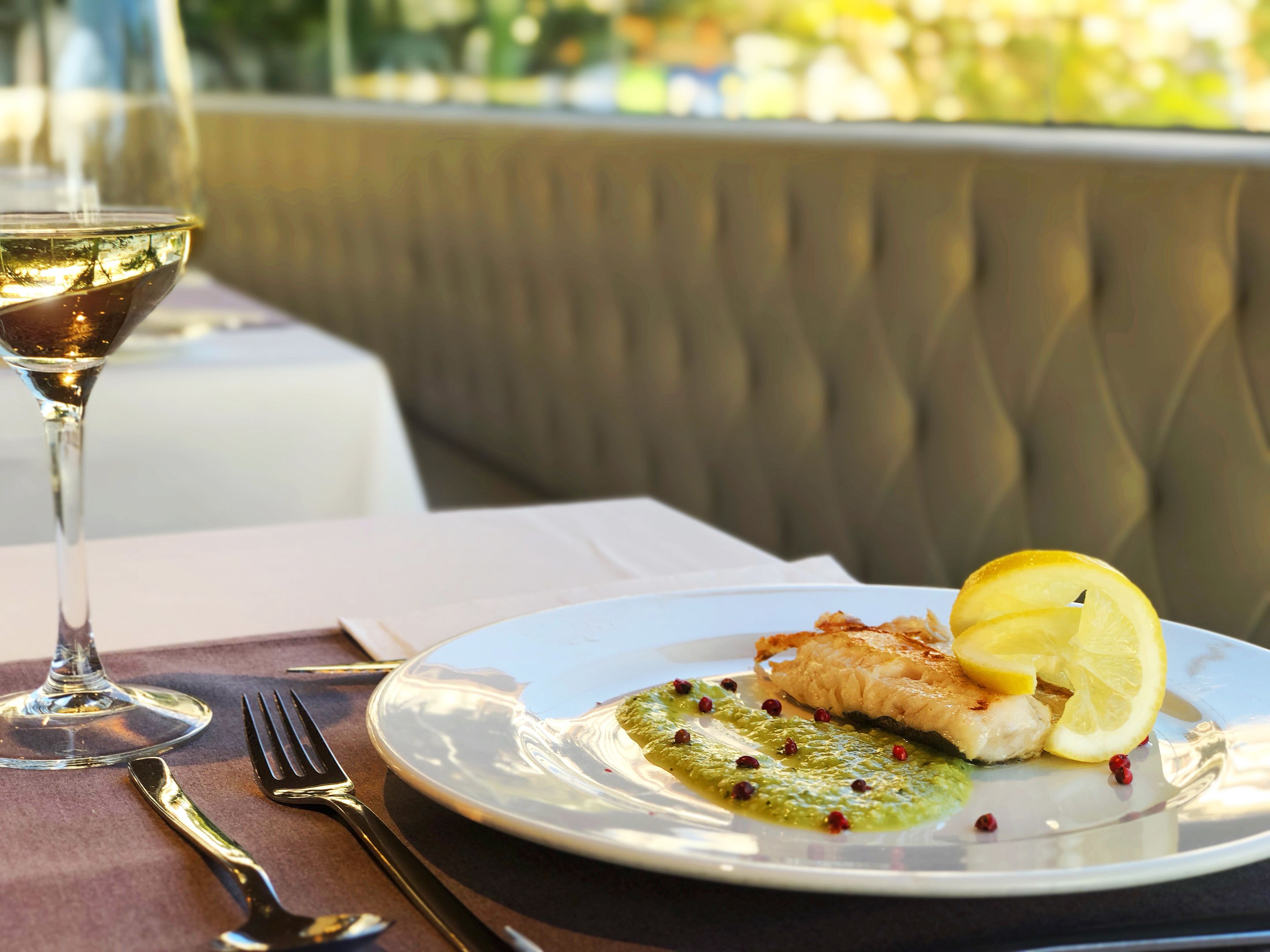 A dining table with a plate of food, a glass of wine, and cutlery.