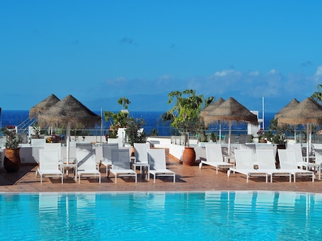 Una piscina al aire libre, camas de piscina gratis, sombrillas