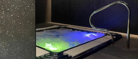 A heated stone bath with a metal faucet and a textured floor.