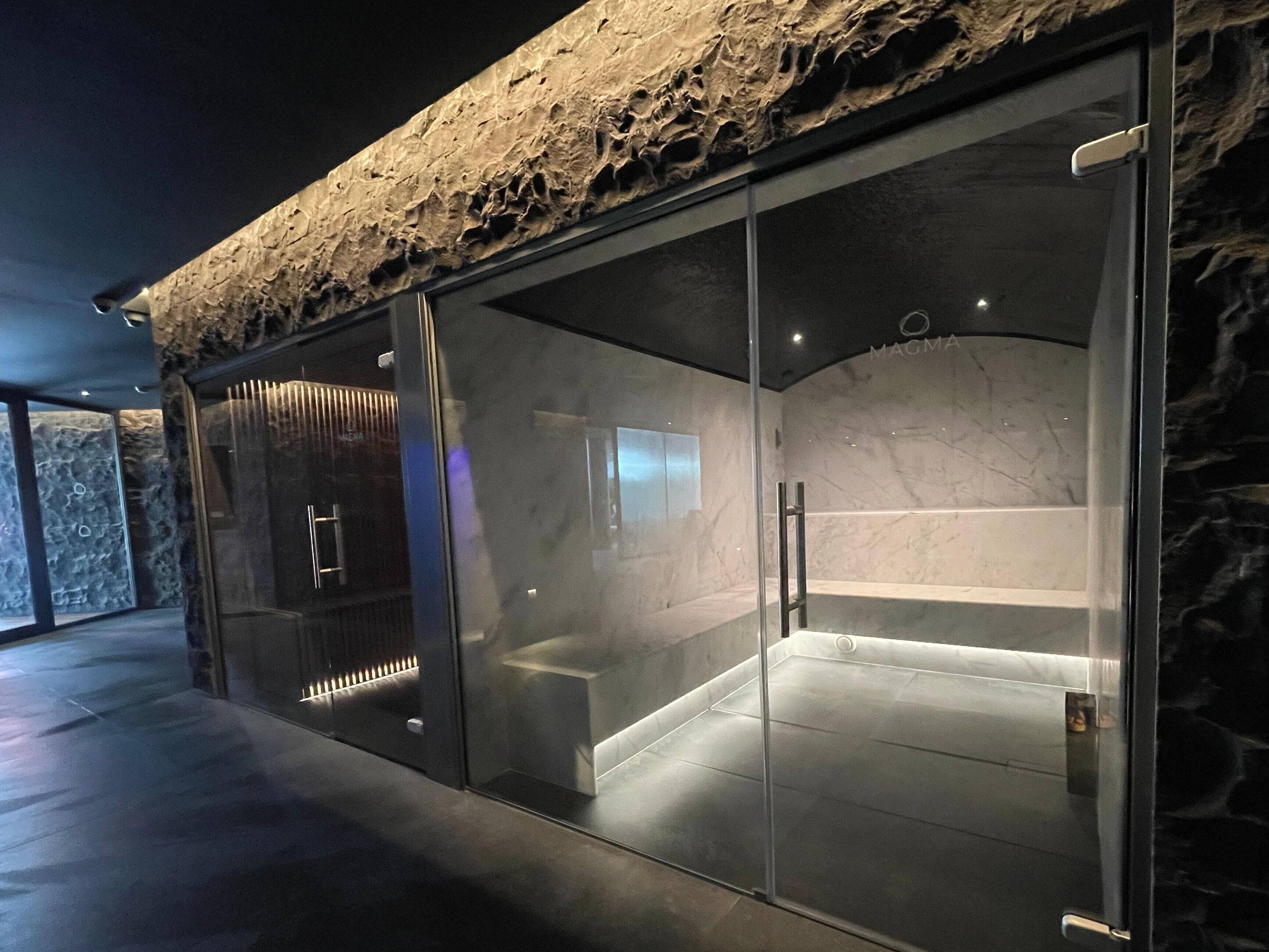 Un spa moderno con fachada de piedra, puertas de vidrio y un interior de mármol.