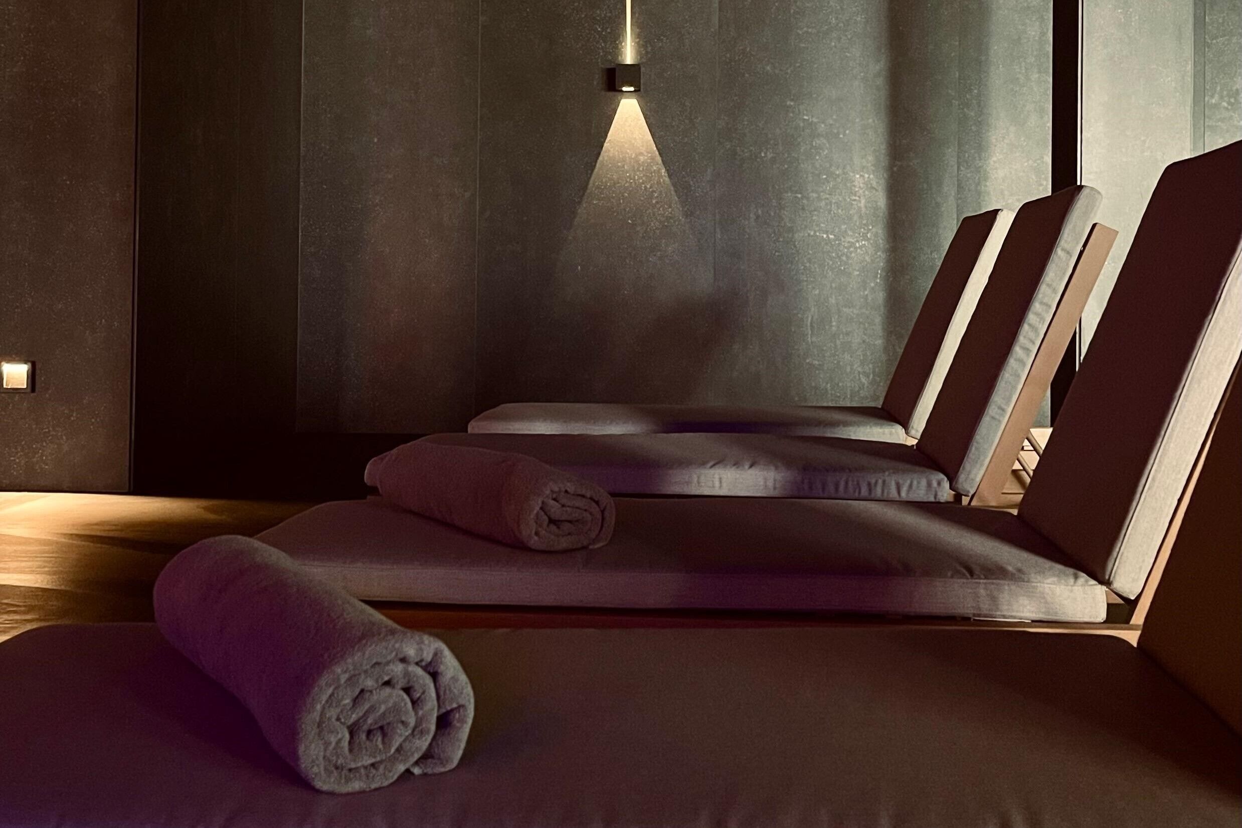 Een spa-ruimte met massagetafels, handdoeken en een wandlamp.