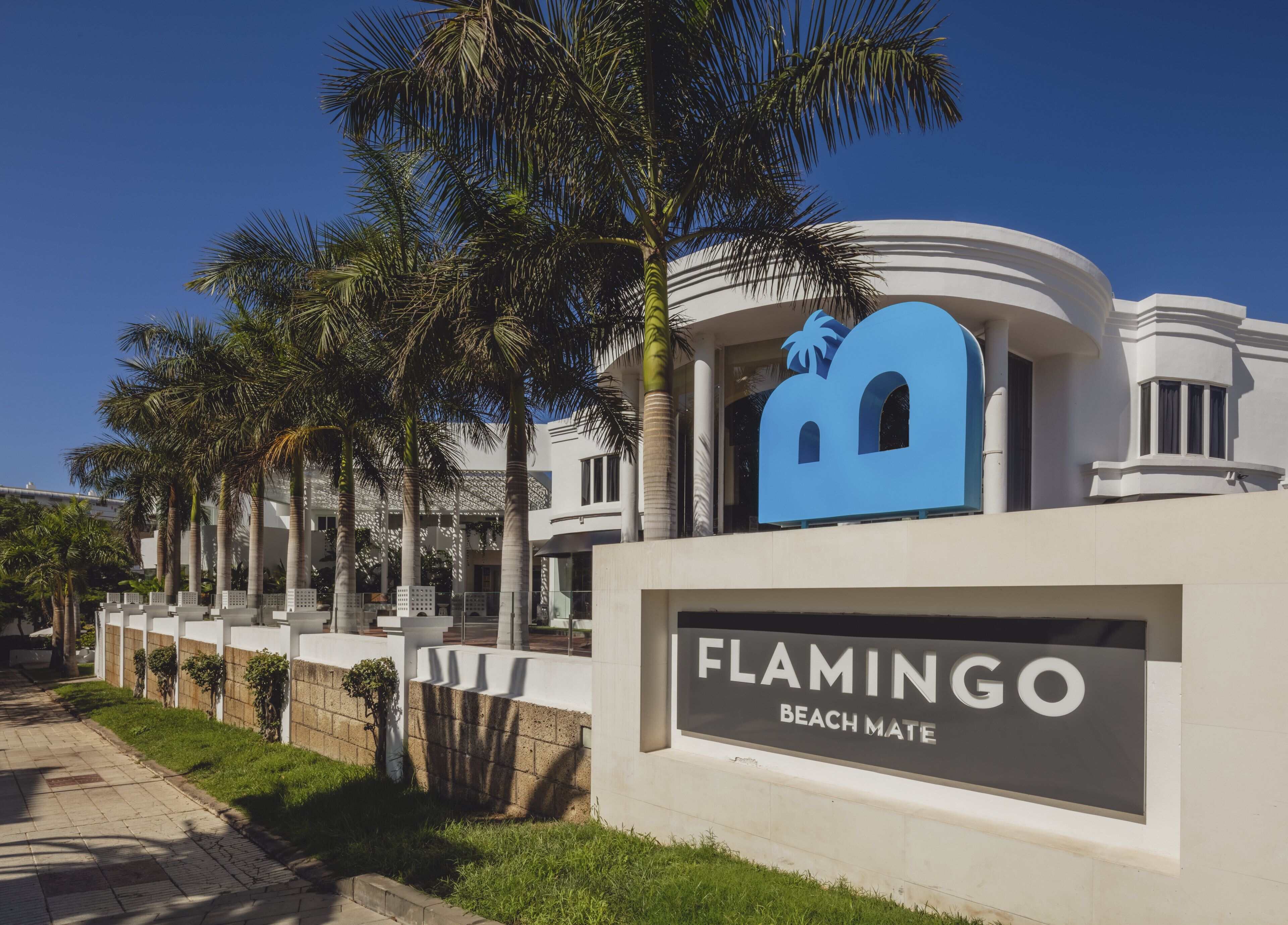 A modern building with a prominent sign reading "FLAMINGO BEACH MATE".
