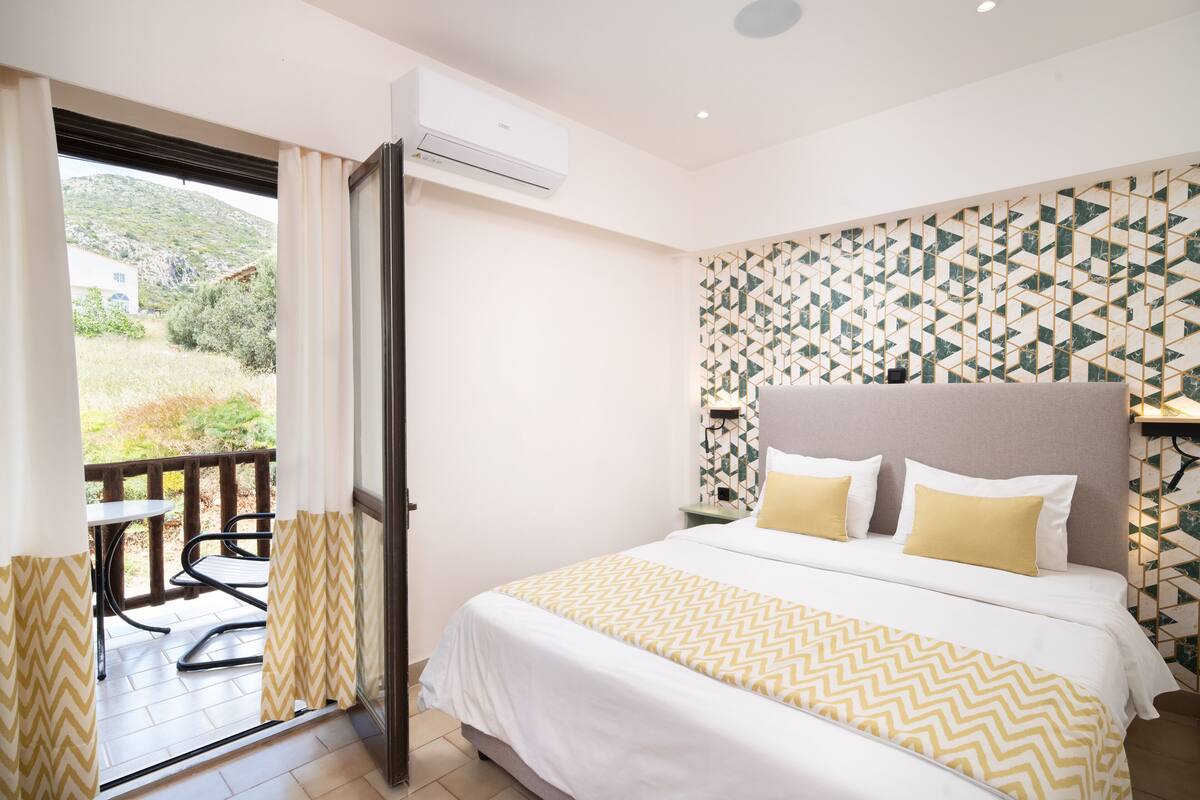A hotel room with a bed, a balcony, and a patterned wall.