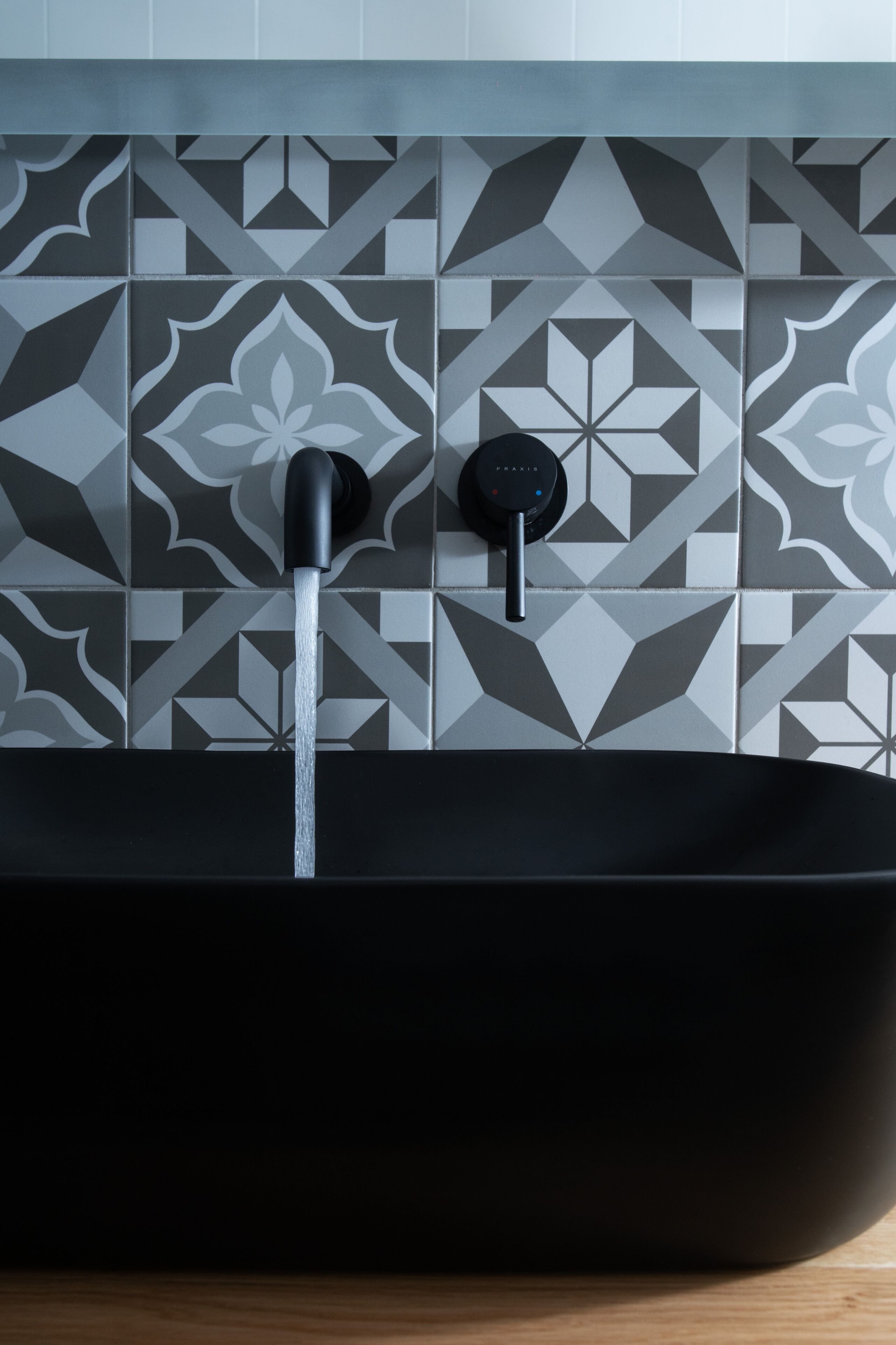 Un baño moderno con una bañera independiente negra, un grifo y un panel de control en la pared.