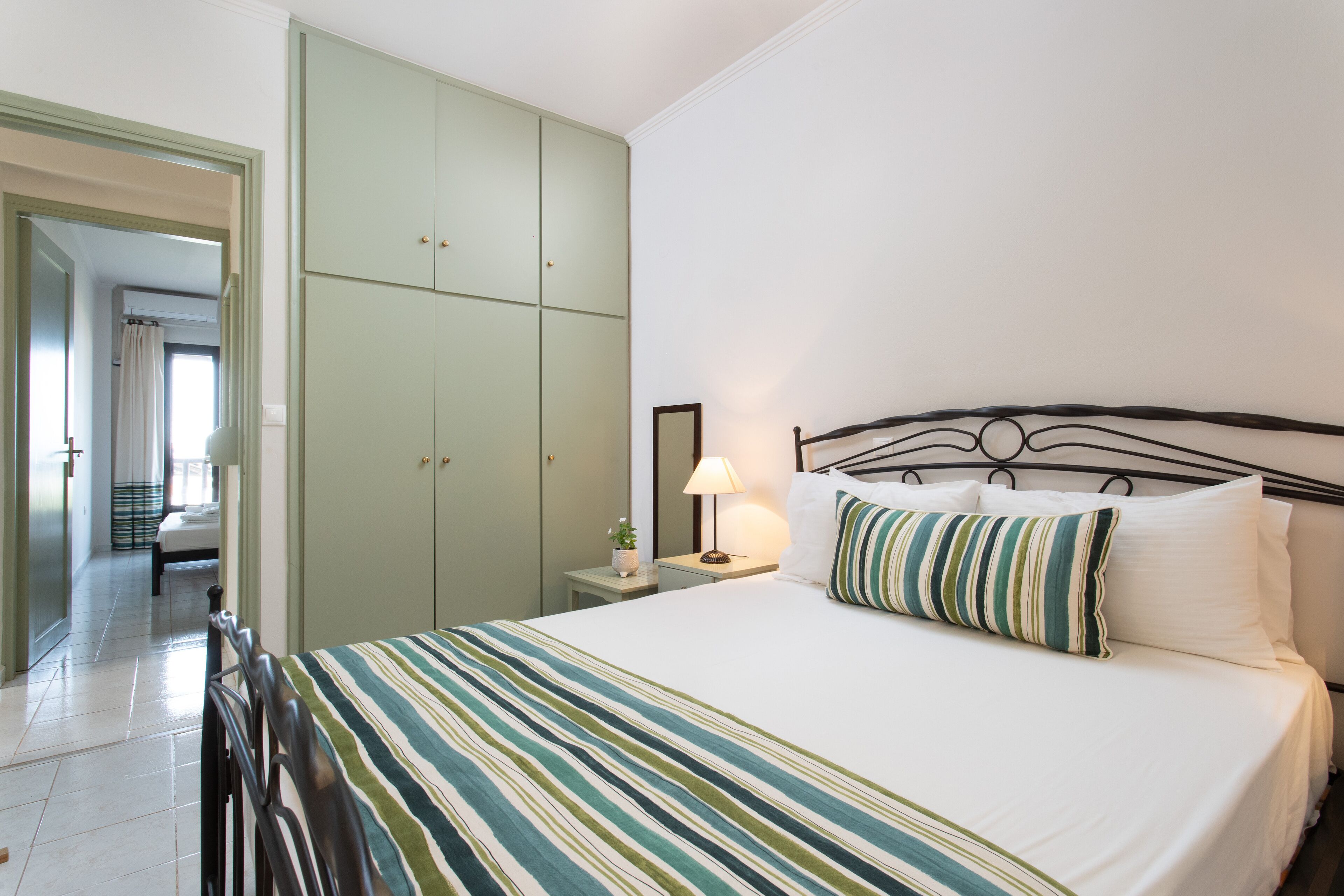 A hotel room with a bed, a nightstand, a lamp, and a wardrobe.