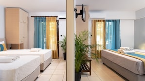A hotel room with two beds, a TV, air conditioning, curtains, and a potted plant. - Monemvasia Green Apartments (Monemvasia)