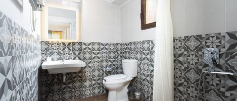 A bathroom with a toilet, sink, and shower.