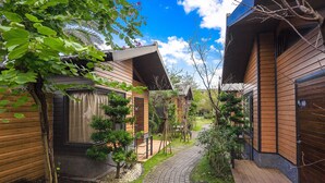 A pathway leading to wooden cabins with a garden view. - Pokara Resort (Jiaoxi)