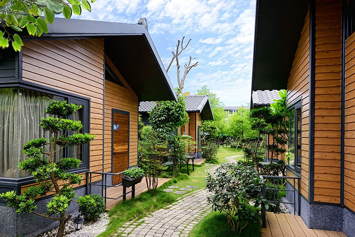 A modern building with wooden siding and a brick pathway leading to a wooden deck.