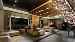 A modern living room with a sofa set, a coffee table, a decorative cabinet, and a piano. - Pokara Resort (Jiaoxi)
