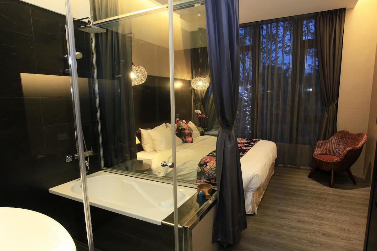 A modern bathroom with a glass shower enclosure, a white bathtub, and a large mirror.