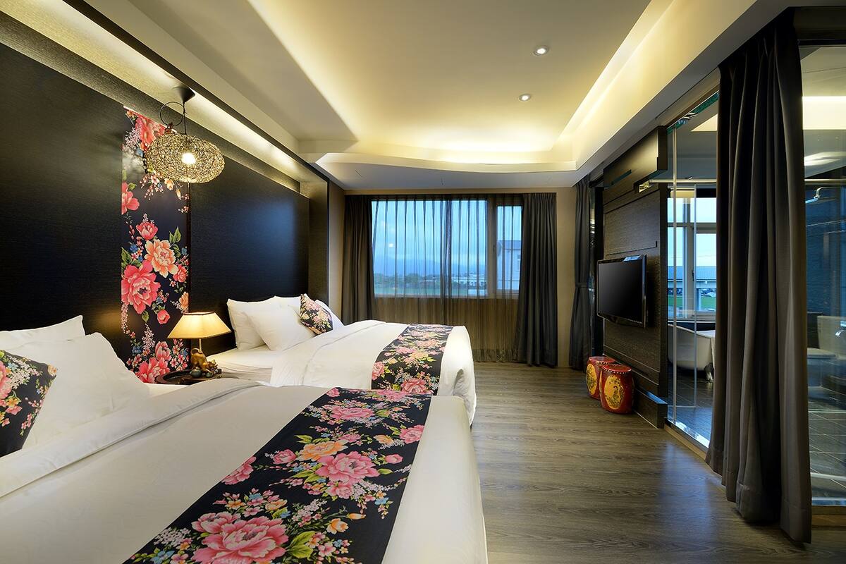 A hotel room with a large bed, a TV, and a view of the cityscape.