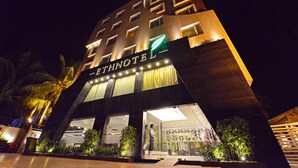 Un hotel moderno con un cartel llamativo, grandes ventanales y una entrada bien iluminada.