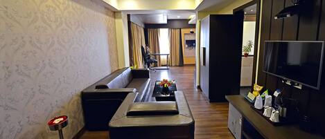 A modern living room with a sofa, a coffee table, a TV, and a small bar area.