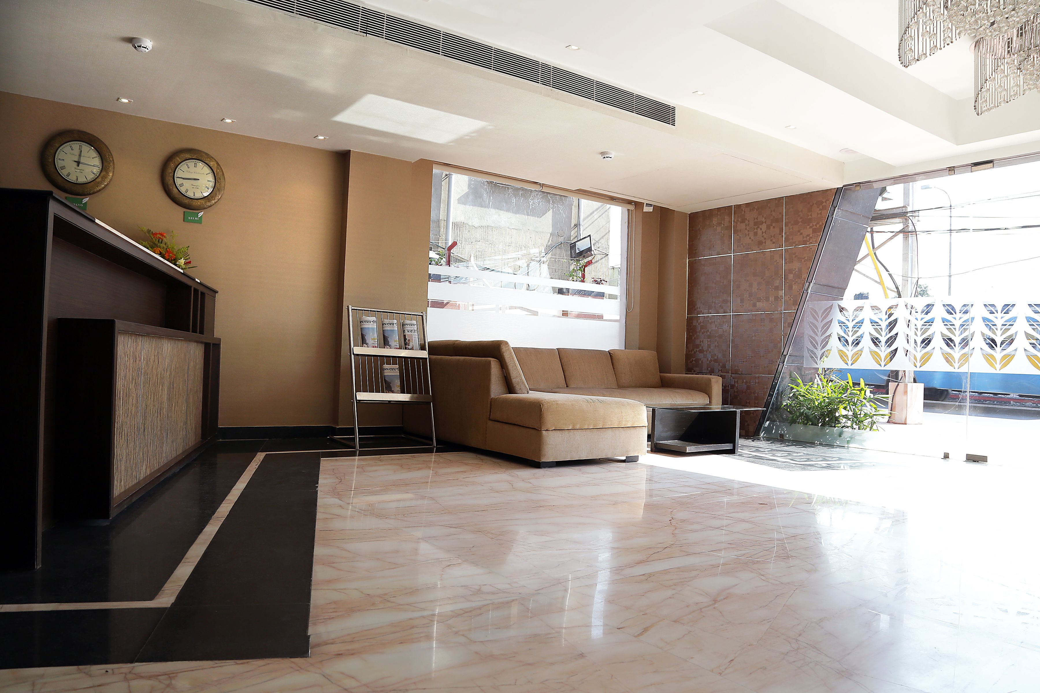 A modern lobby with a reception desk, a sofa, and a large window.