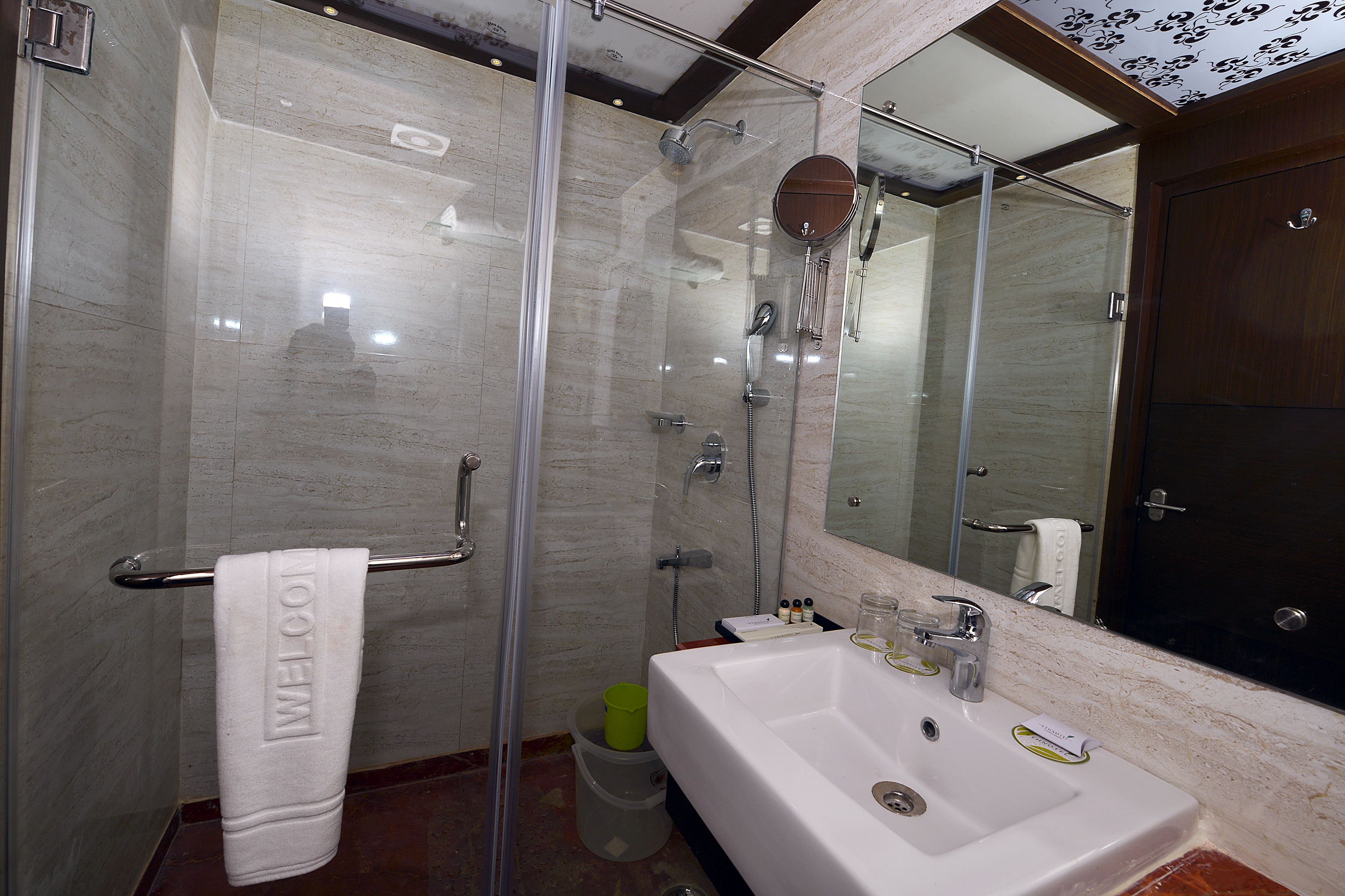 A modern bathroom with a glass-enclosed shower, a white sink, and a large mirror.