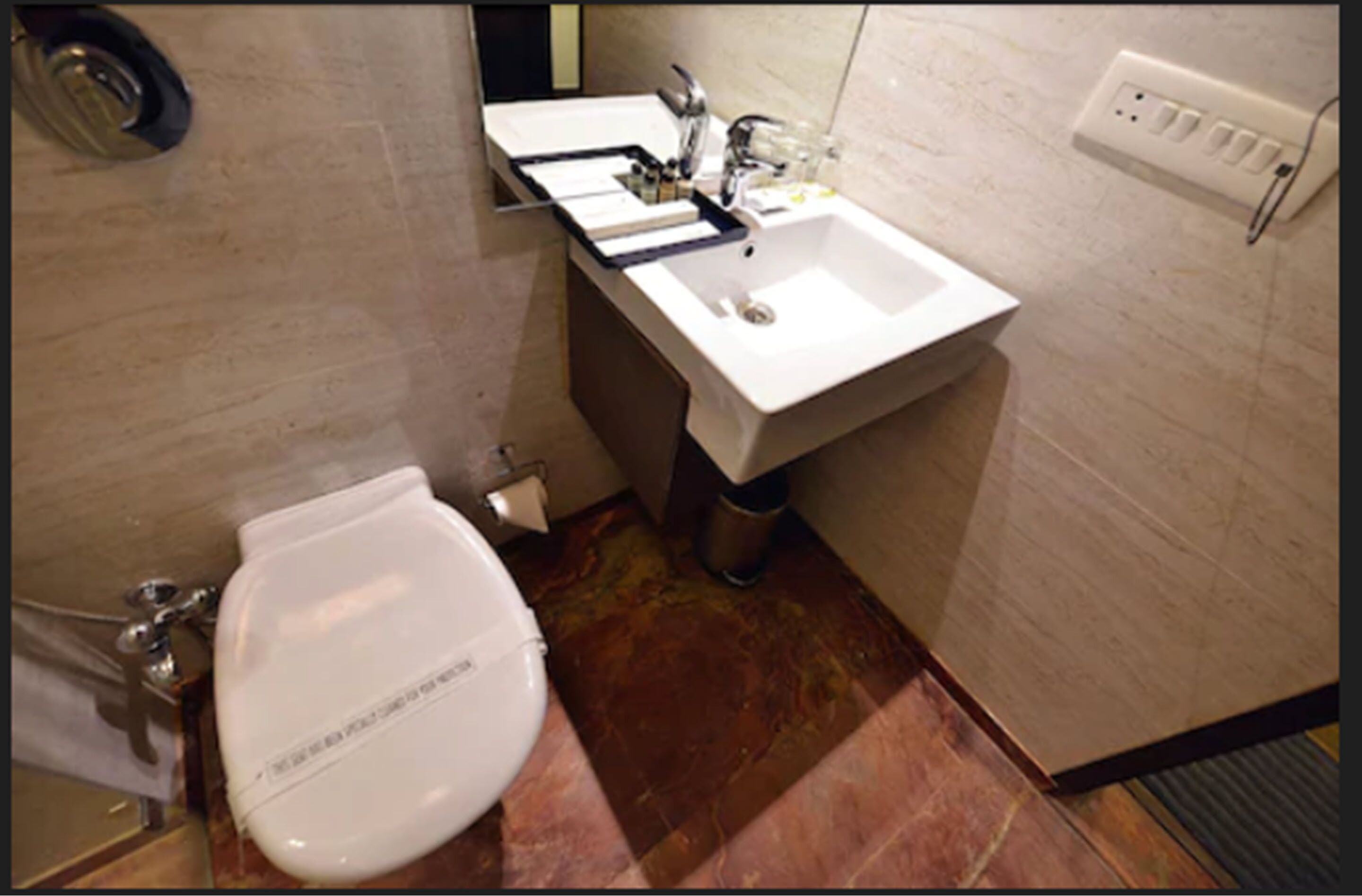 Une salle de bain avec des toilettes blanches, un lavabo et un miroir.