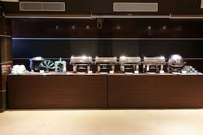 A buffet setup with multiple food stations, each with a glass container and a dome cover. - Ethnotel, Kolkata Airport (Barakpur)