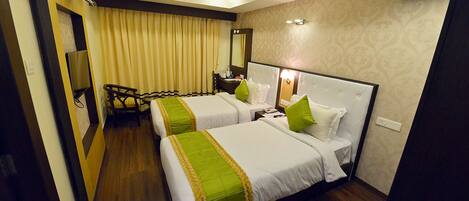 A hotel room with two beds, a desk, a chair, a mirror, and a television.
