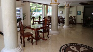 Un vestíbulo espacioso con techos altos, columnas ornamentales y un amplio comedor con mobiliario de madera.
