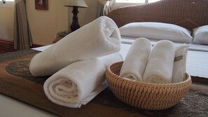 A neatly arranged set of towels on a tray and in a basket, with a bed and a lamp in the background. - Lalco AR Hotel (Vientiane)