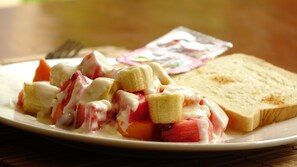 A plate with fruit salad and toast. - Lalco AR Hotel (Vientiane)