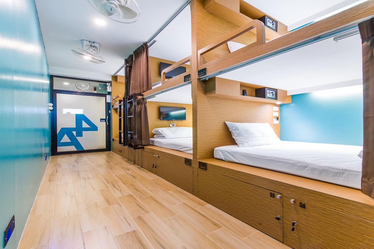 Dormitorio con literas, suelo de madera, televisión y cortina.