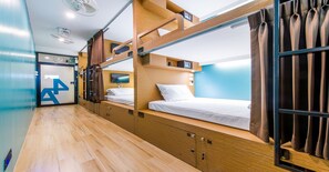A bunk bed room with a wooden floor, a TV, and a curtain.