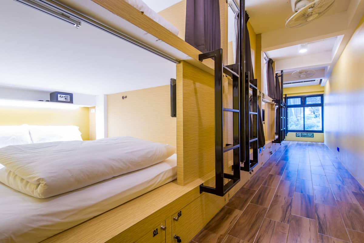Habitación de hotel con cama, piso de madera, ventana y puerta.